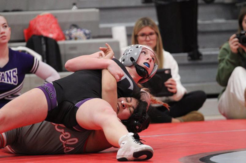 Two girl wrestlers on a red mat.