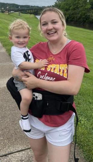 Kimberlyn stands outside, holding her son.