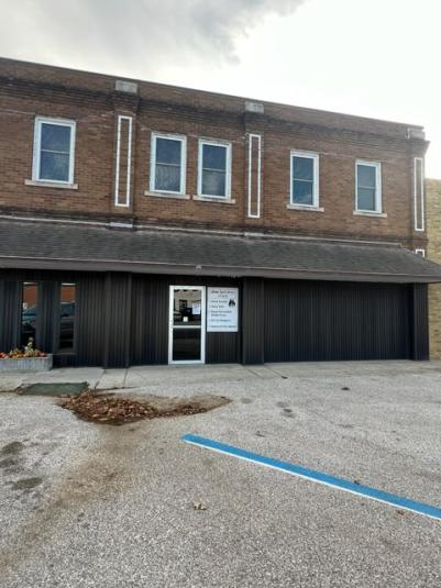 A photo of the exterior of Annex I office building. The upper level is a medium brown brick with several rectangular windows. The street level story is a darker brown with the same color canopy.