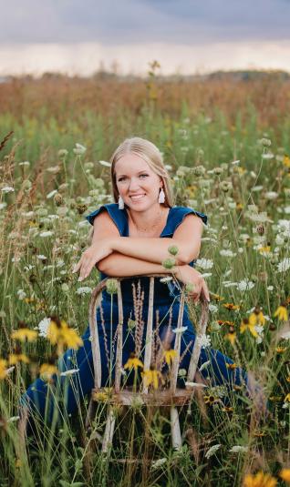 Schleisman sits on a wooden chair in the middle of a field of flowers.