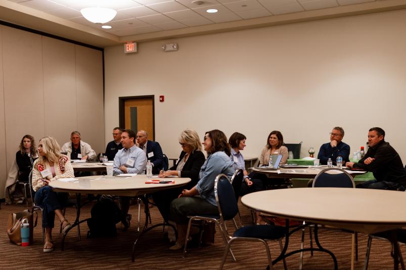 Members of the BOOST Steering Committee sit at circular tables in a conference room.