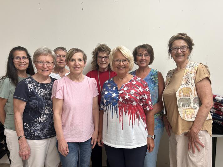 Eight members of the Calhoun County Republic Women stand in two rows, facing the camera. One woman is wearing a white vest with yellow and gray elephants embroidered on it. Another woman is wearing an American-flag themed red, white, and blue T-shirt. 
