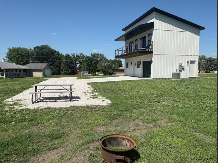 A far away shot of the two homes that currently make up CJ Resort Twin Lakes. On the left, in the background, is an older, one story tan house. In the foreground is brand new white two story house.