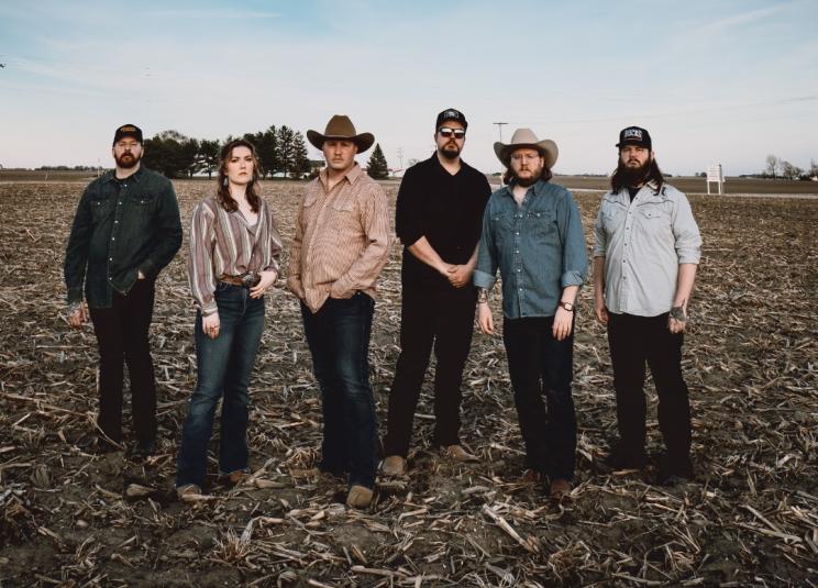 Band members stand in a harvested cornfield. 