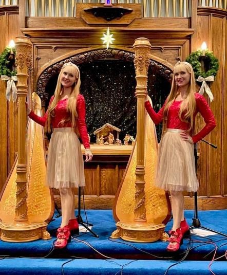 The Kitts stand facing the camera, each with their right hand on a large wooden harp.