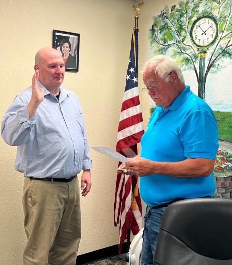 James stands facing the mayor, with his right hand raised during his swearing in.