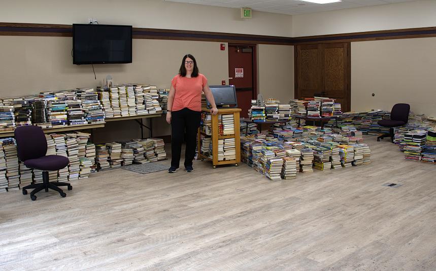 Hardiman stands against a far wall, facing the camera, with stacks of books on either side of her.