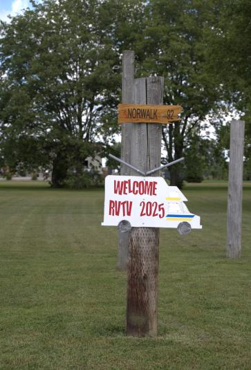 A white wooden sign in the shape of an RV reads "Lohrville RVTV 2025."
