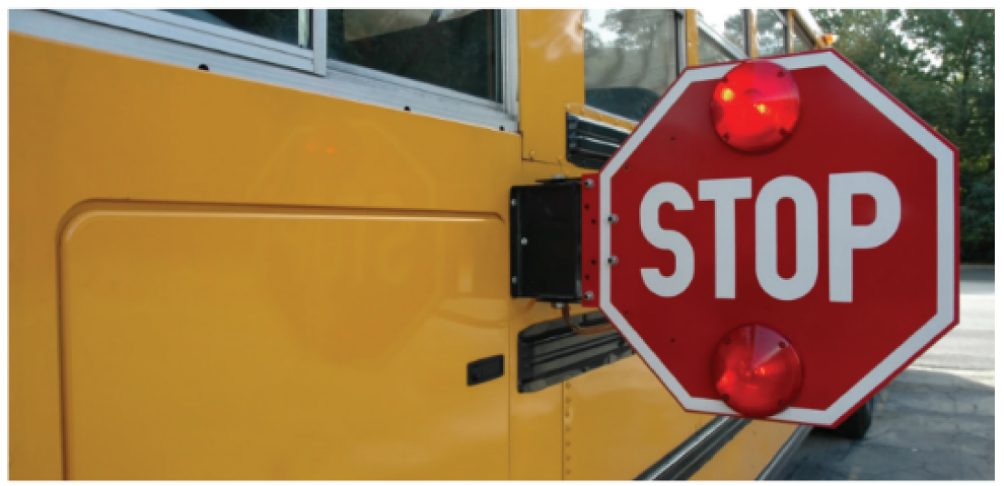 A close-up of a stop sign extended from the side of a yellow school bus.