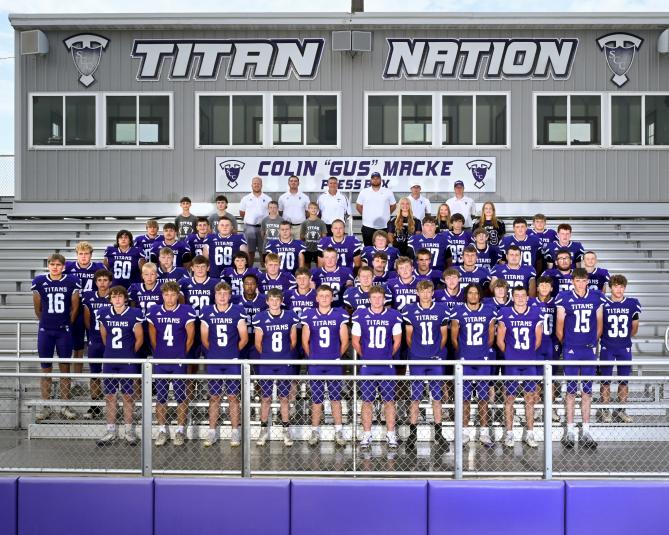 The players in uniform stand on the bleachers for a group photo, along with their coaches.